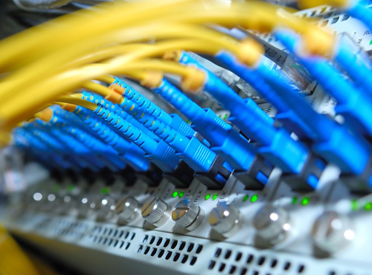 Blue fibre optic connectors and yellow cables connected to network equipment